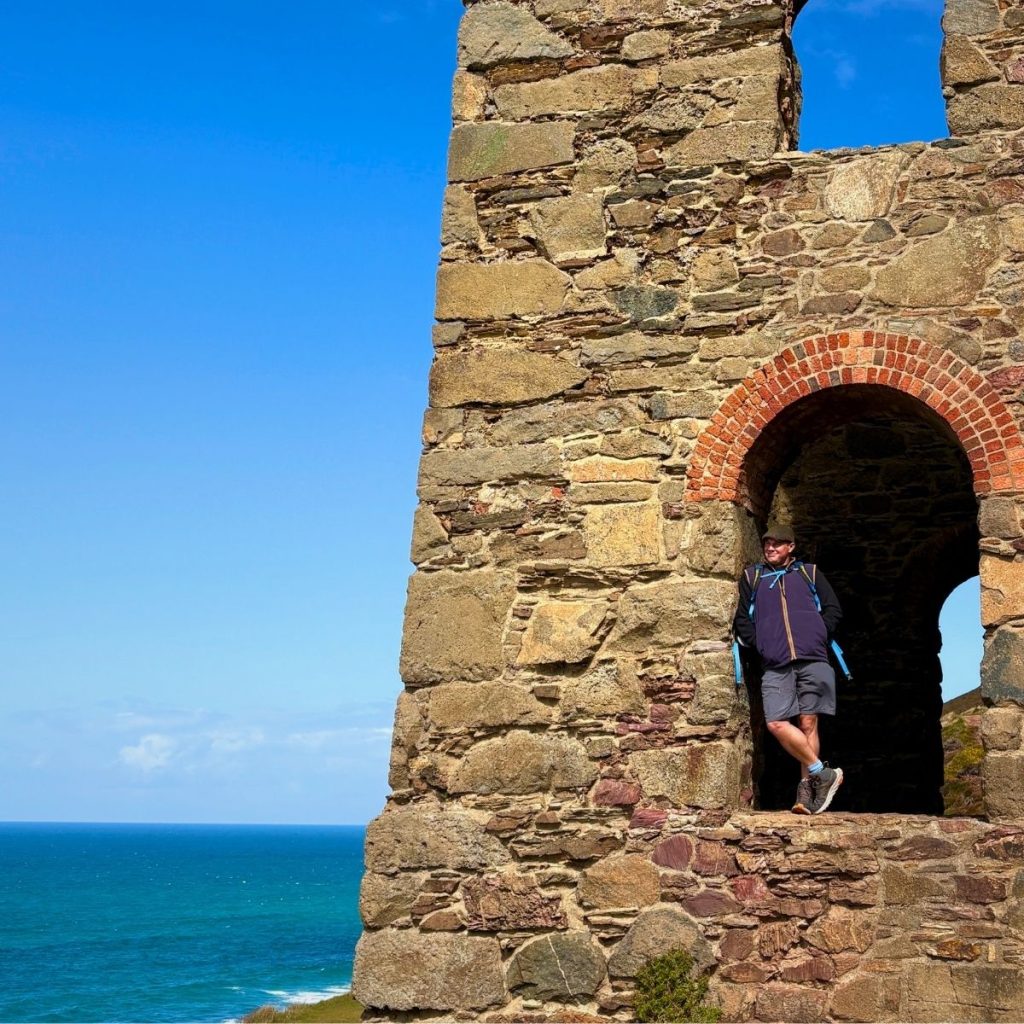 Man stood in archway of Wheal Coates mine in St Agnes looking out to see smiling