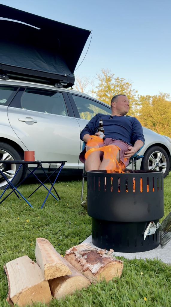Dan relaxing beside a campfire at Cambrose Camping & Touring during a TentBox Diaries adventure in Cornwall.