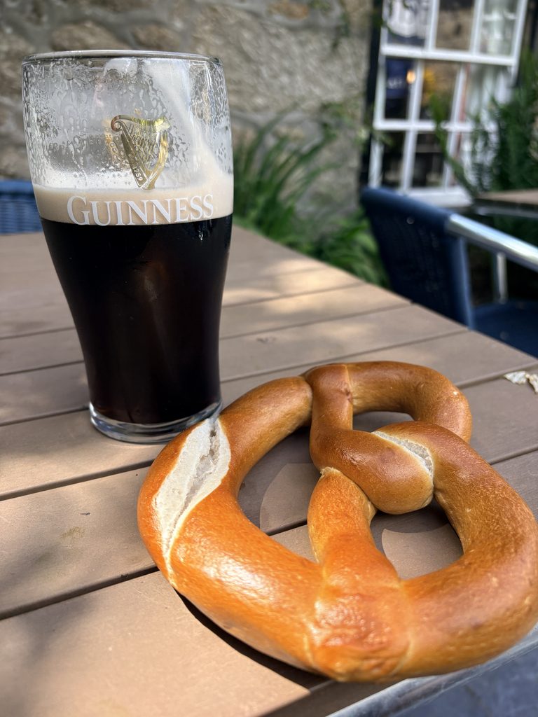 Pint of Guinness and a pretzel on an outdoor table at The Logan Rock Inn in Treen, Cornwall.